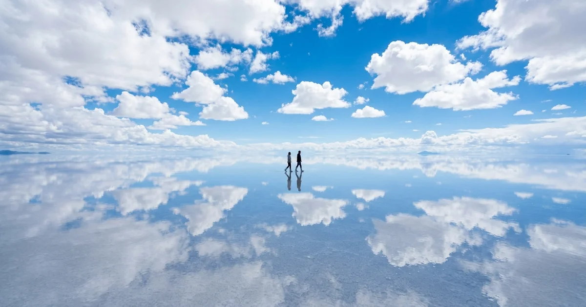 Surreal Natural Phenomena - A massive flat landscape entirely covered in a thin layer of water that perfectly reflects the blue sky and fluffy white clouds above it.